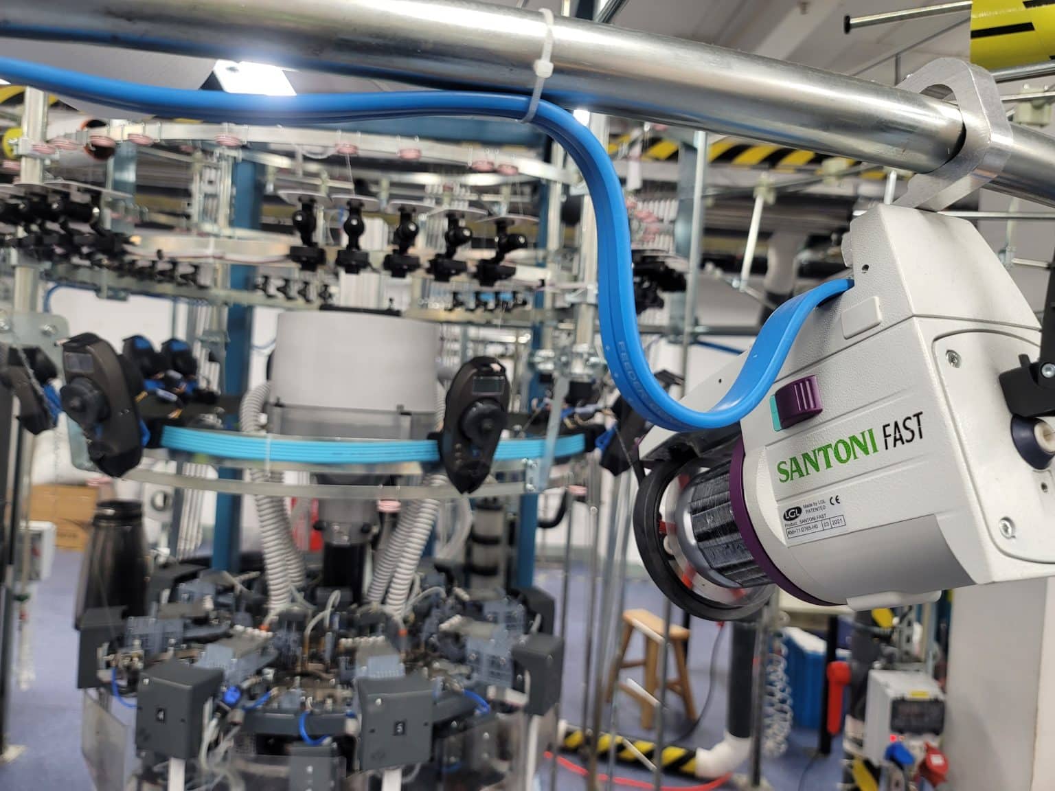 Close-up of a Santoni seamless knitting machine processing synthetic fibers, demonstrating exactly what is yarn made of for premium activewear.